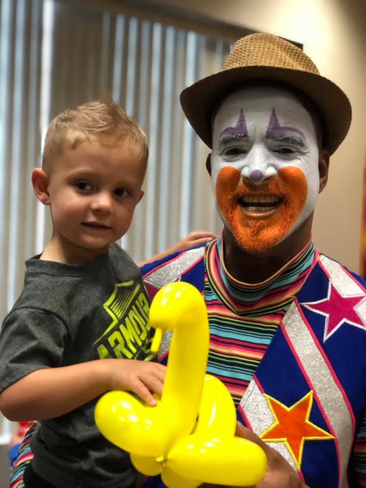 Geebo the Clown holding one of our tiny patrons