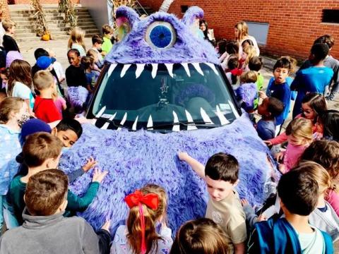 A purple, furry art car with fan interactions 