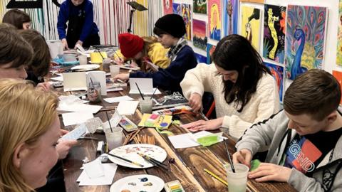 Teens painting art around a table